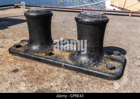 Große schwarze Liegeplatz Poller montiert auf konkrete Pier im Hafen Stockfoto