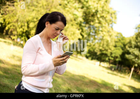 Trauriges Mädchen wischte sich eine Träne während des Lesens einer SMS-Nachricht Stockfoto