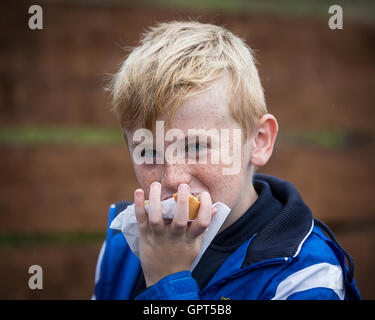 Jung, lächelnd, blonden Jungen halten und eine Torte mit einer Hand Essen Stockfoto