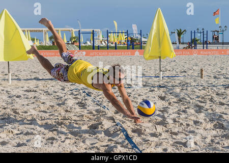 Junger Mann in Bewegung spielt im Beach-Volleyball. Stockfoto