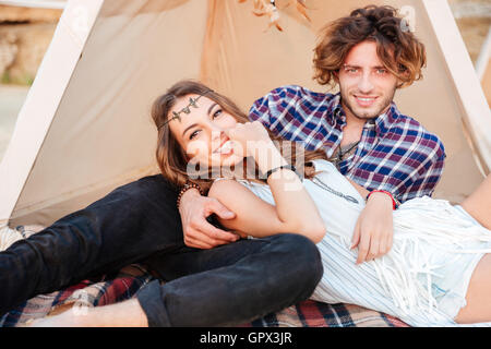 Fröhliches junges Paar im Tipi am Strand liegend Stockfoto