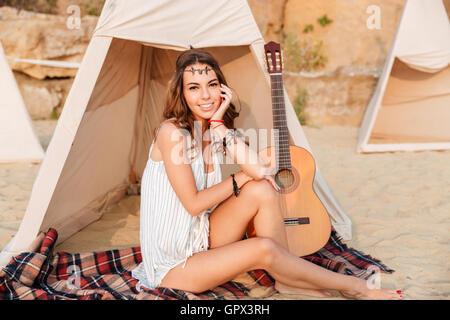 Schöne Brünette Hippiemädchen sitzt am Zelt und Blick in die Kamera Stockfoto