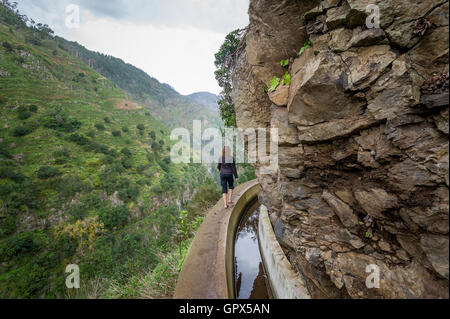 Frau zu Fuß am Fußweg entlang der felsigen Klippen. Levada Nova Wanderung, die Insel Madeira. Stockfoto