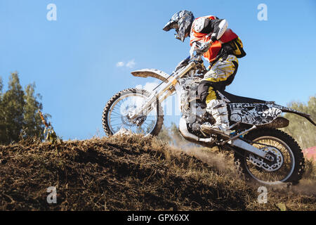 Sportler-Racer auf einem Motorrad fährt bergauf auf einer staubigen Strecke während Ural Cup in Enduro Stockfoto