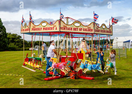 Kinder reiten auf A traditionelle Karussell (Karussell), die jährliche Hartfield Dorffest, Hartfield, East Sussex, UK Stockfoto