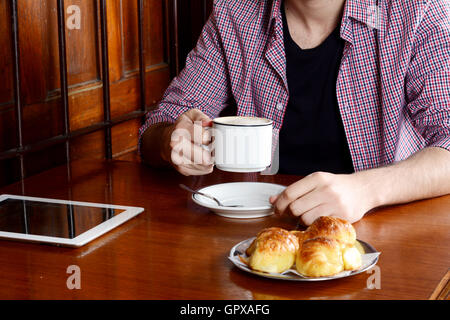 Nahaufnahme eines Mannes mit digital-Tablette und trinken Kaffee in einem Café. Im Innenbereich. Stockfoto