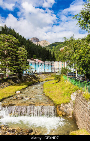 Bergfluss fließt durch Dorf in den Alpen Stockfoto