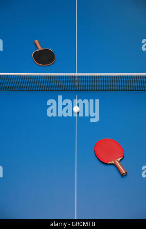 Tischtennisschläger blau rot und schwarz und eine Kugel auf eine Tischtennisplatte, Ansicht von oben Stockfoto