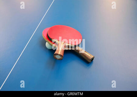 Tischtennisschläger rote Farbe und einen Ball auf eine Tischtennisplatte, Ansicht von oben Stockfoto