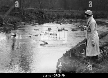 1930er Jahre, historische, eine elegante junge Dame trug einen Mantel und Hut stehend Angeln am Ufer des Flusses Rye, North Yorkshire, England. Stockfoto