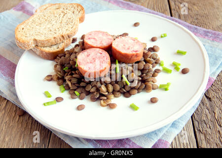 Grüne Linsensuppe mit Wurst (Schlackwurst) auf weißen Teller Stockfoto