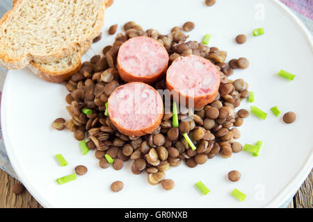 Grüne Linsensuppe mit Wurst (Schlackwurst) auf weißen Teller Stockfoto