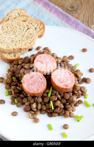 Grüne Linsensuppe mit Wurst (Schlackwurst) auf weißen Teller Stockfoto