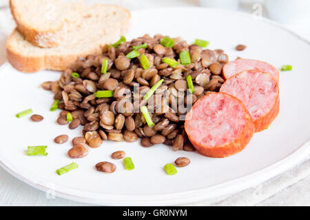 Grüne Linsensuppe mit Wurst (Schlackwurst) auf weißen Teller Stockfoto