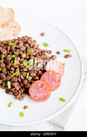 Grüne Linsensuppe mit Wurst (Schlackwurst) auf weißen Teller Stockfoto