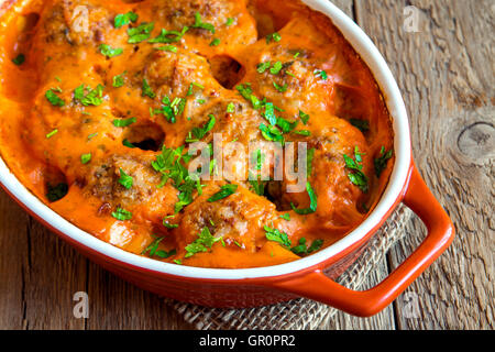 Hackfleischbällchen mit Tomatensauce und Petersilie in Auflaufform über rustikale Holz Hintergrund Stockfoto
