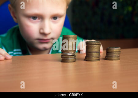 Glückliches Kind (junge, Kind, Teenager) Münzen auf dem Tisch stapeln. Kinder und zählen Geld-Konzept. Stockfoto