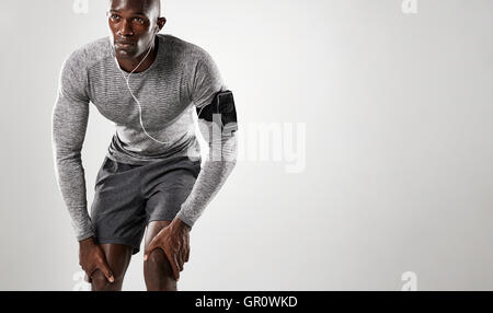 Junge Afrikaner mit Armbinde und Kopfhörer auf grauem Hintergrund stehend und wegsehen. Stockfoto