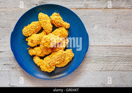 Hausgemachte gebackene knusprige Chicken Wings auf eine blaue Keramik-Platte Stockfoto