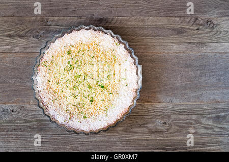 Zitrone, Limette, Kokosnuss unmöglich Torte mit weißer Schokolade Späne auf einem verwitterten Holztisch Stockfoto