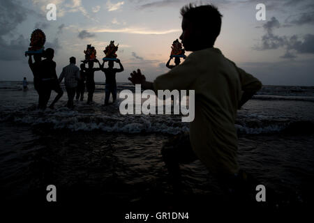 Mumbai, Indien. 6. September 2016. Ein Junge läuft über das Wasser, wie Menschen Idole der hindu-Gott Ganesha auf dem Kopf vor dem Eintauchen ins Meer während des zweiten Tages des Ganesh Festivals am 6. September 2016 in Mumbai, Indien tragen. Bildnachweis: Chirag Wakaskar/Alamy Live-Nachrichten Stockfoto