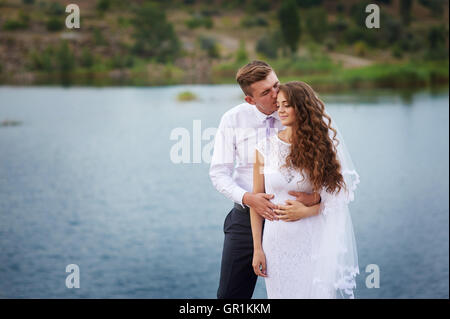 schöne junge Paare, die nahe dem See am Tag Hochzeit Stockfoto