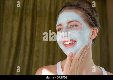 junge Frau tut kosmetische Maske im Gesicht Stockfoto
