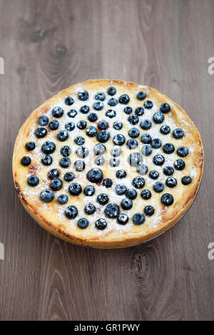 Frisch gebackener Heidelbeerkuchen auf Holztisch. Delisious süße Nachspeise zu Hause gebacken. Hausgemachte Bio-Teig, Beeren und Zucker-Pulver. Senkrecht über Kopf gedreht Stockfoto