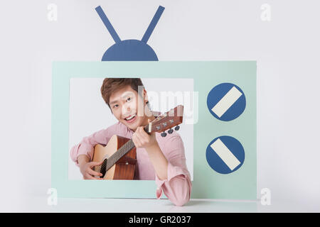 Porträt des jungen lächelnder Mann Gitarre im Fernsehen Stockfoto
