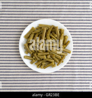Draufsicht einer Portion Bio geschnittene grüne Bohnen auf eine gestreifte Tischdecke. Stockfoto