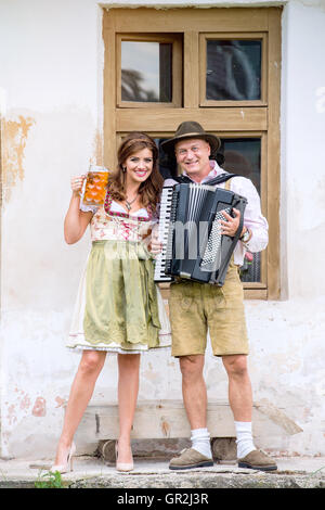 Paar in bayerischer Tracht mit Bier und Akkordeon Stockfoto