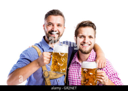 Männer in bayerischer Tracht Becher Bier halten Stockfoto