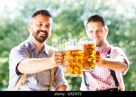 Männer in bayerischer Tracht Becher Bier halten Stockfoto