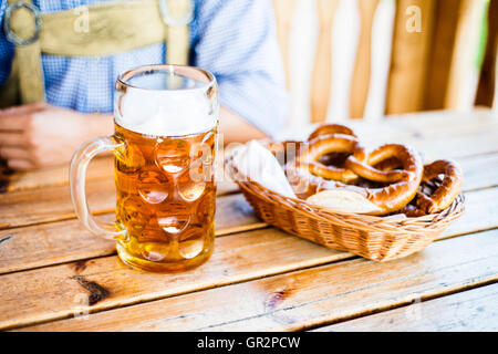 Mann in bayerischer Tracht mit Bier und Brezeln Stockfoto