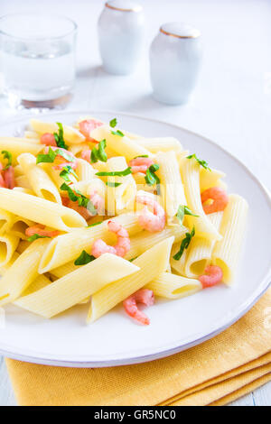 Penne-Nudeln mit Garnelen und Petersilie auf weißem Hintergrund Stockfoto