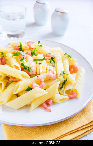 Penne-Nudeln mit Garnelen und Petersilie auf weißem Hintergrund Stockfoto