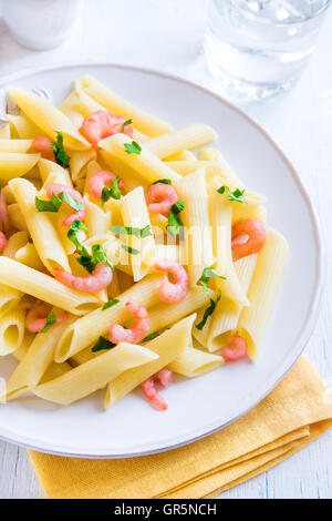 Penne-Nudeln mit Garnelen und Petersilie auf weißem Hintergrund Stockfoto