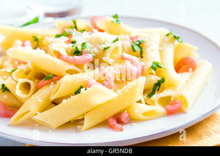 Penne-Nudeln mit Garnelen und geriebenem Parmesan auf weißem Hintergrund Stockfoto