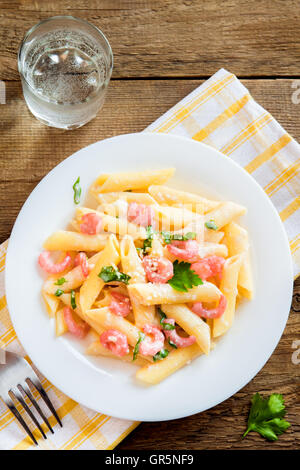 Penne-Nudeln mit Garnelen, Sahne-Sauce und geriebenem Parmesan auf hölzernen Hintergrund Stockfoto