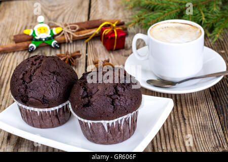 Schoko-Muffin mit Kaffee und Weihnachtsbaum-Hintergrund Stockfoto