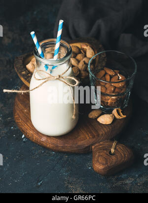 Frische Mandelmilch in Glasflasche mit Mandeln serviert Stockfoto