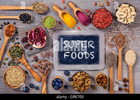 Super-Lebensmittel in Löffel und Schalen auf einem hölzernen Hintergrund Stockfoto