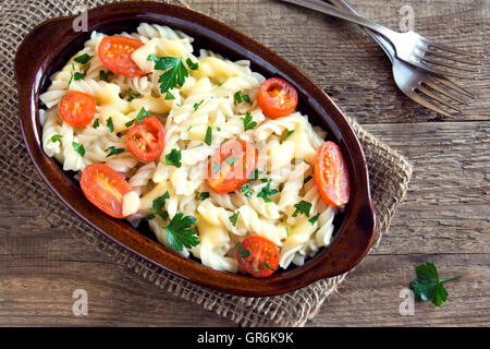 Pasta-Auflauf mit Cherry-Tomaten, Käse und Kräutern über rustikale Holz Hintergrund Stockfoto