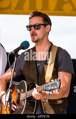 Broadstairs folk Woche. Junger Mann folk Sänger Gitarrist, trug eine dunkle Sonnenbrille, die im Musikpavillon. Nahaufnahme von Sänger und Gitarre. Stockfoto