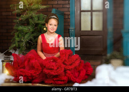 Kleines Winter begrüßt Prinzessin in eine kostbare Krone im roten Kleid Weihnachten und Neujahr in zauberhafte Weihnachten Innenraum Stockfoto