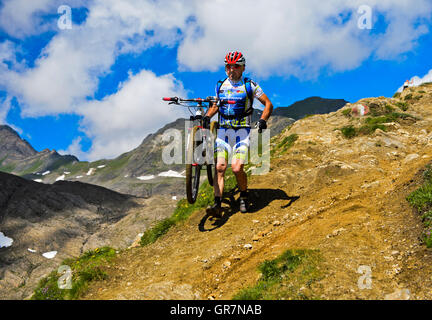 Mountainbiker trägt das Fahrrad auf einem steilen Pfad in der Nähe von Corno Gries Hütte, Tessin, Schweiz Stockfoto