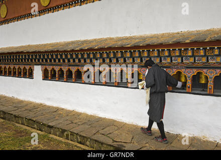 Junger Mann drehen Gebet Mühlen, Kloster Glockenspiel Lhakhang in der Nähe von Lobesa, Bhutan Stockfoto