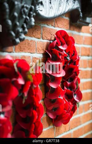 Eine Gedenkstätte Wand mit Mohn Kränze und Palque mit Namen der Toten. Stockfoto