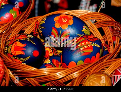 Ostereier bemalt In blau mit Rot Orange Blumen im Korb Stockfoto