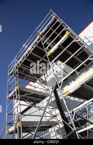 Ein großes Gerüst Arbeitsbühne mit einer Aluminium-Tower-System erstellt. Steht neben einem Lagergebäude Stockfoto